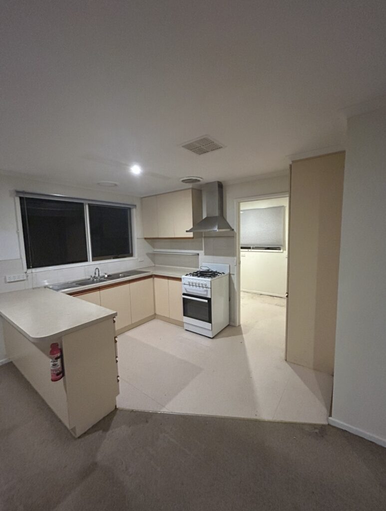 U-shaped kitchen with beige cabinets, white countertops, and a window over the double sink.